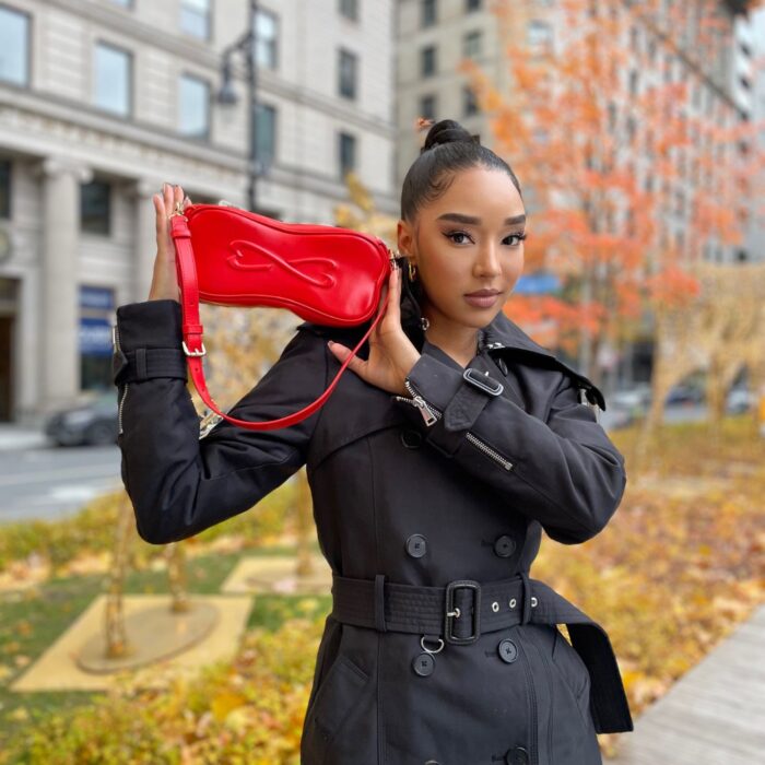 Model holding small leather red bag.